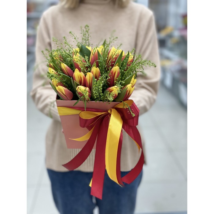 Красно-жёлтые тюльпаны в коробке с зеленью