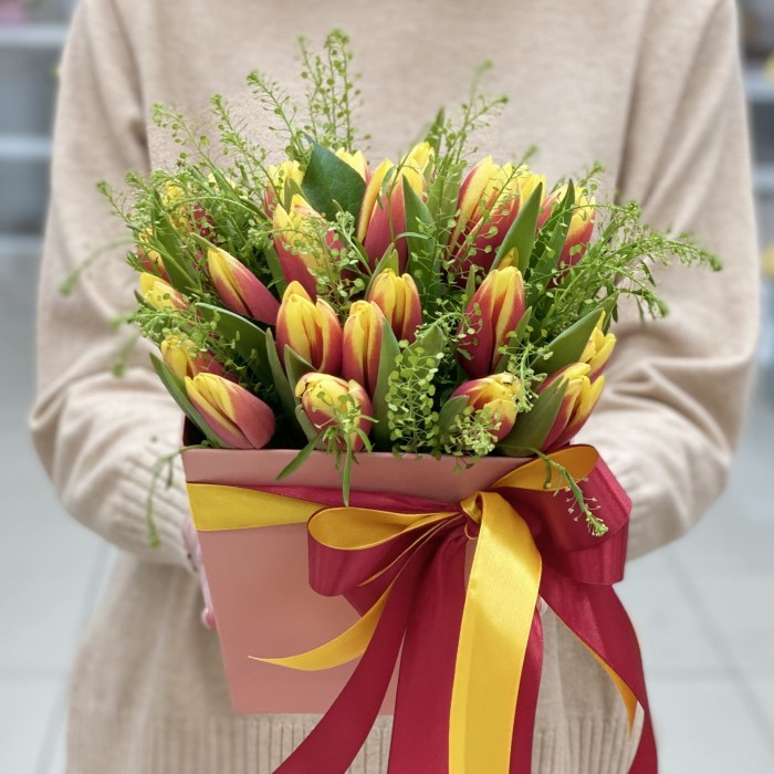 Красно-жёлтые тюльпаны в коробке с зеленью