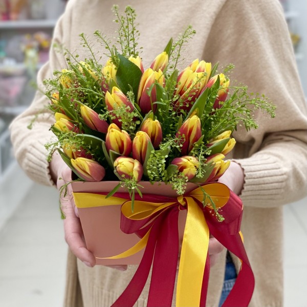 Красно-жёлтые тюльпаны в коробке с зеленью