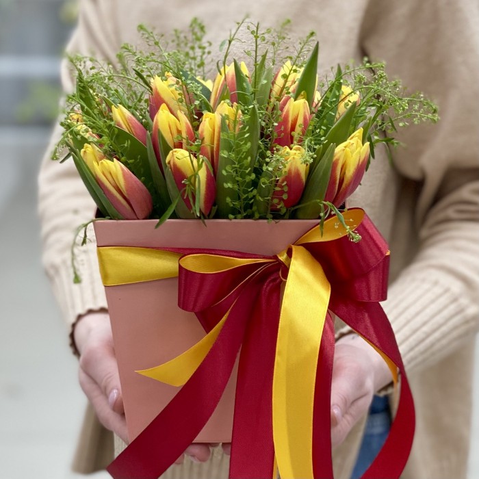 Красно-жёлтые тюльпаны в коробке с зеленью