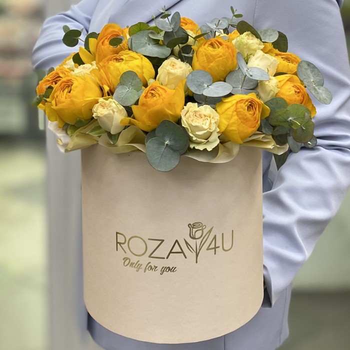 Яркие желтые ранункулюсы в коробке с розами