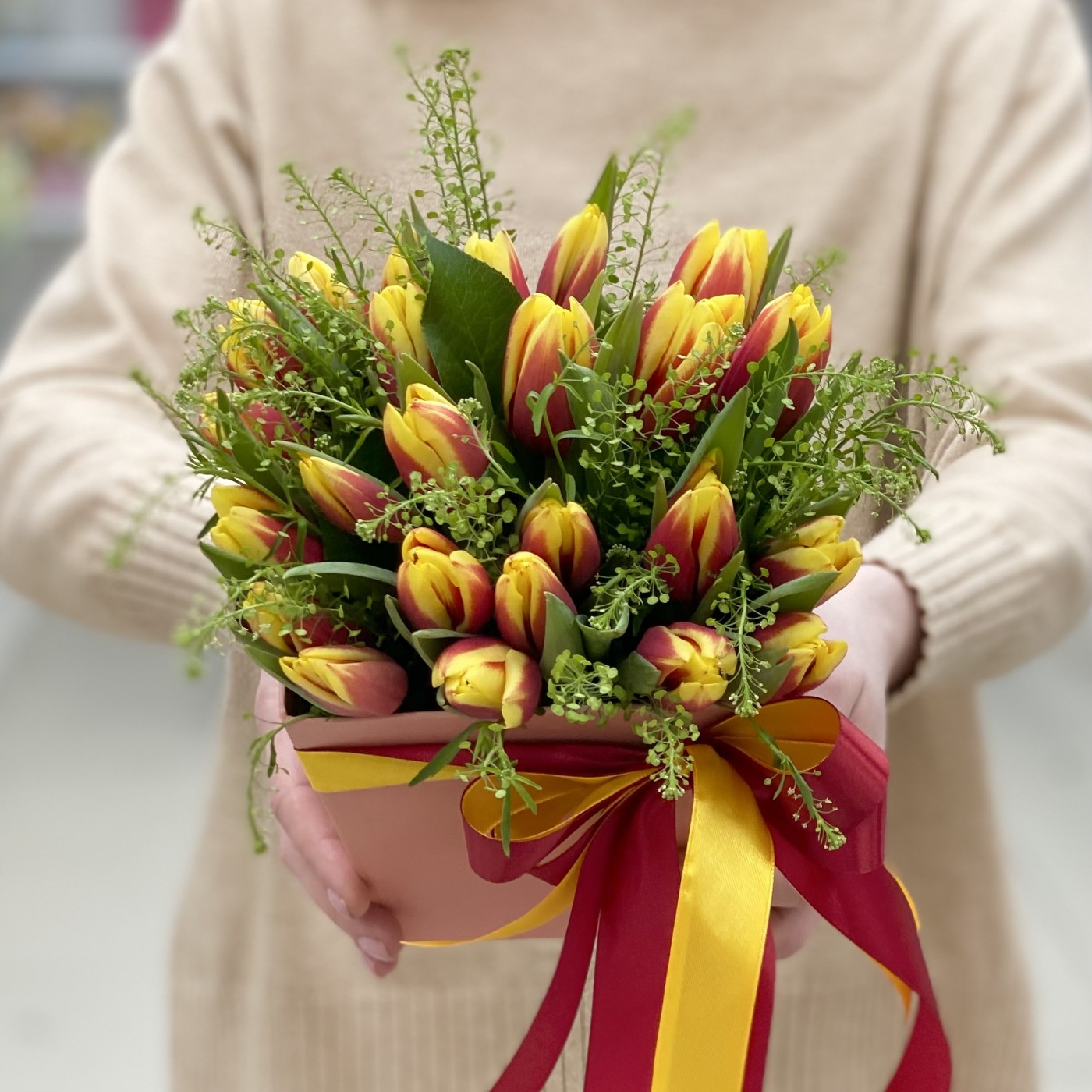 Красно-жёлтые тюльпаны в коробке с зеленью