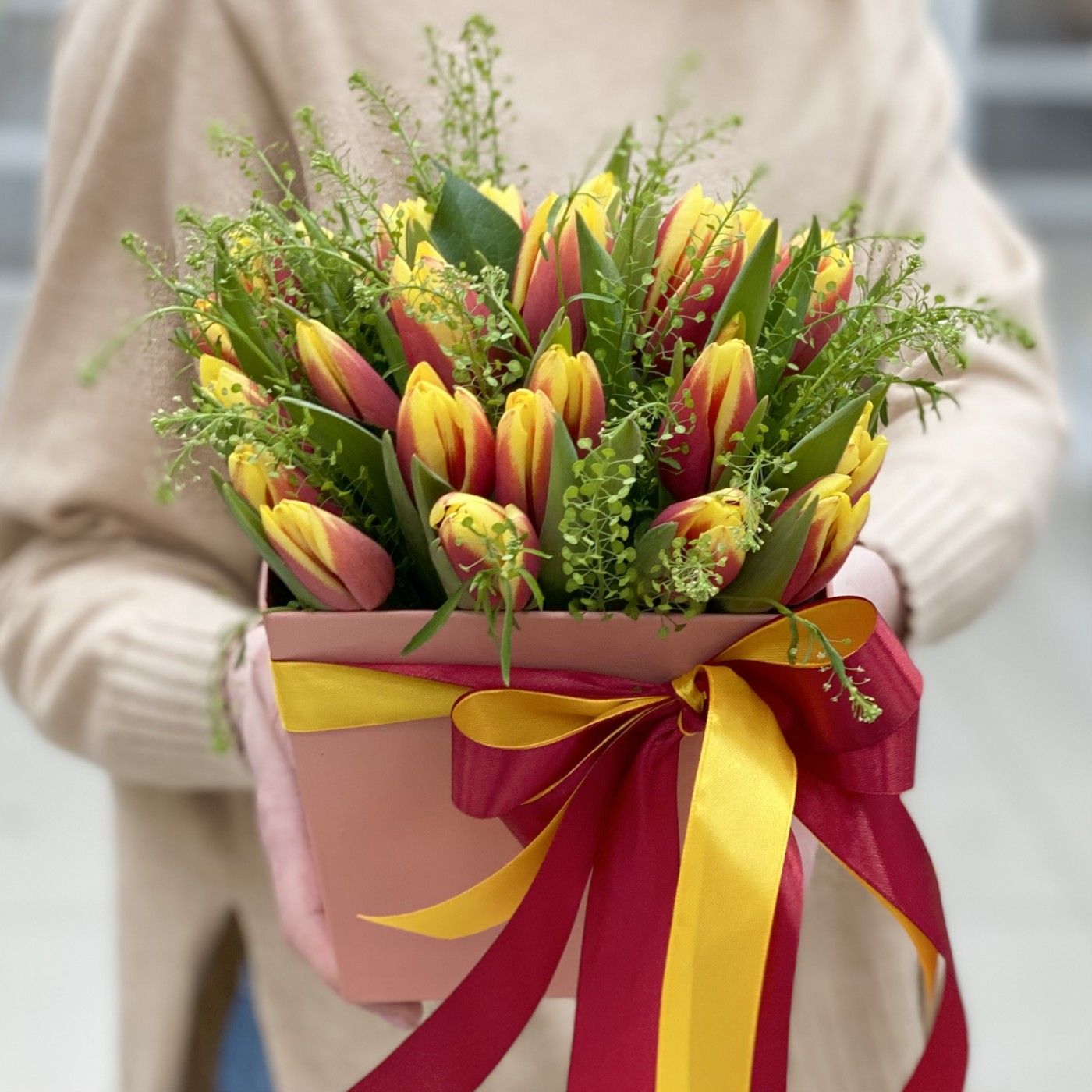 Красно-жёлтые тюльпаны в коробке с зеленью