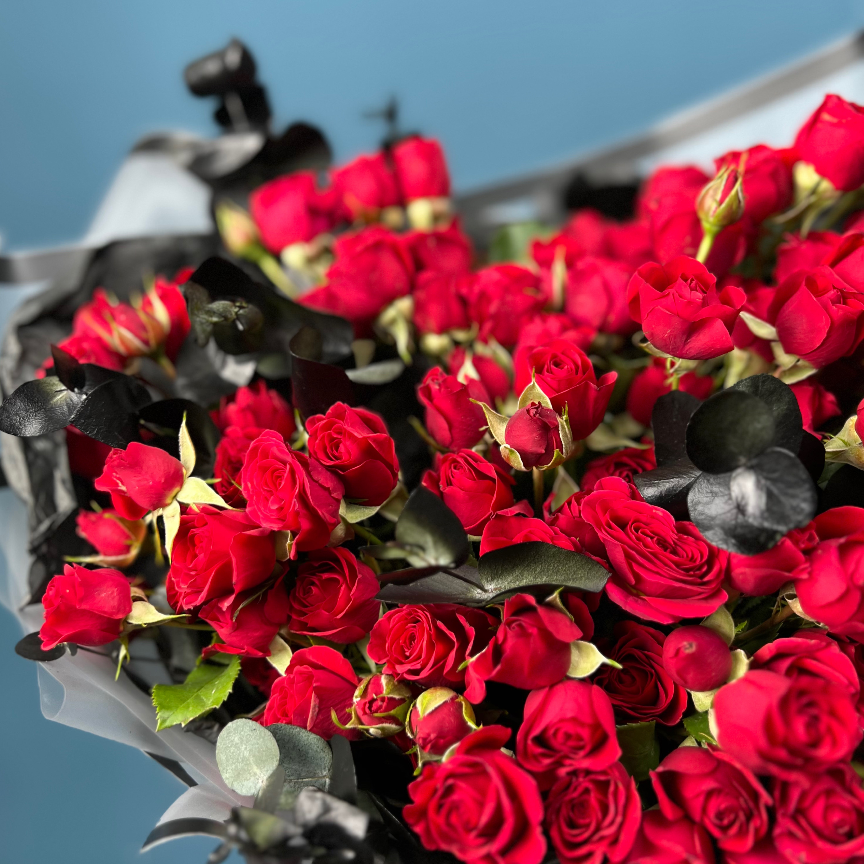 Траурный букет из кустовых красных роз в упаковке